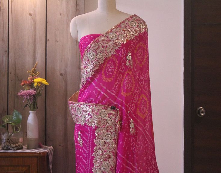 Bringing a gorgeous Pink Pure Crepe Rai bandhej Gota Patti Handwork Saree. The border has a fabulous setting of Gota Patti, Kundan, pearl, zardozi and sequins.. Thus a lot of hard work went into making this masterpiece. Additionally the color is simply superb. Also the blouse piece has work on the back and sleeves. Color : Pink Technique: Gota Patti Fabric: Pure Crepe Blouse Piece: Included Saree Length - 5.5 mtrs The saree will come with Fall & Edging (Complimentary) Blouse stitching servic Traditional Bandhani Print Saree For Reception, Saree With Bandhani Print For Reception, Reception Bandhani Print Saree, Traditional Bandhani Print Dupatta For Reception, Bollywood Traditional Wear With Bandhani Print For Reception, Reception Dupatta With Bandhani Print In Traditional Drape, Bandhani Print Saree For Reception, Reception Saree With Bandhani Print, Bandhani Print Dupatta For Reception And Festivals