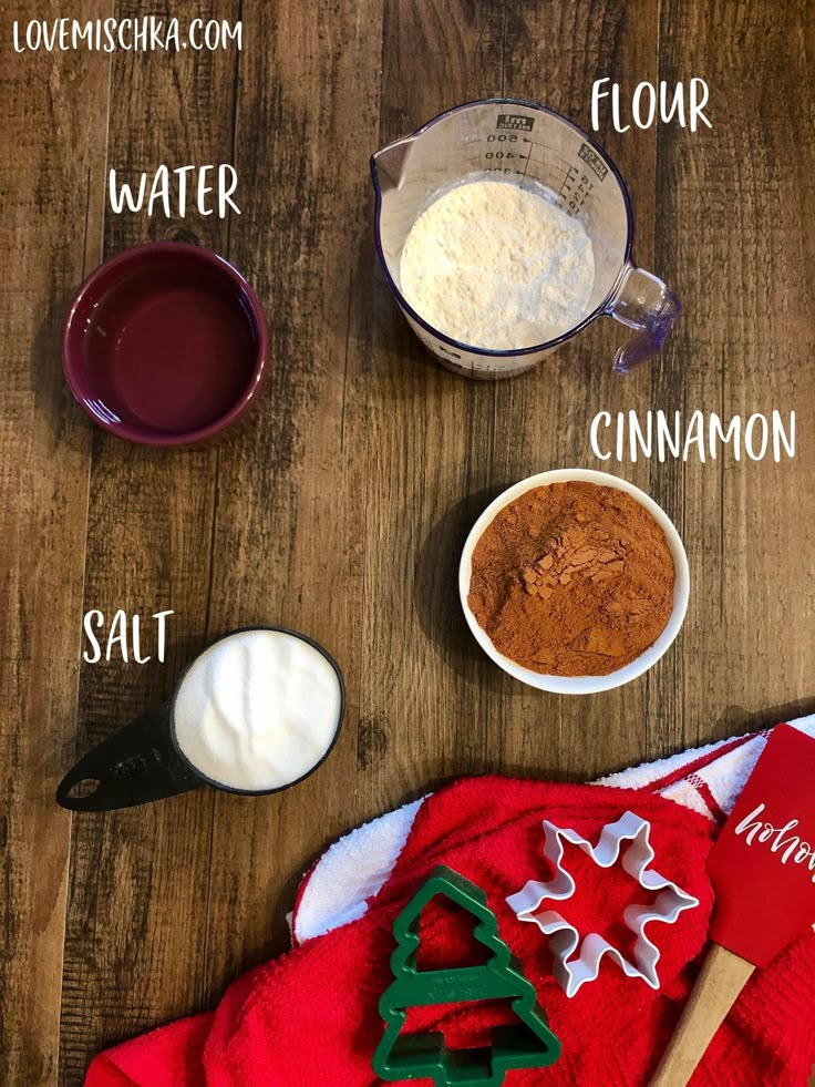 ingredients to make christmas cookies laid out on a wooden table, including flour, sugar and cinnamon