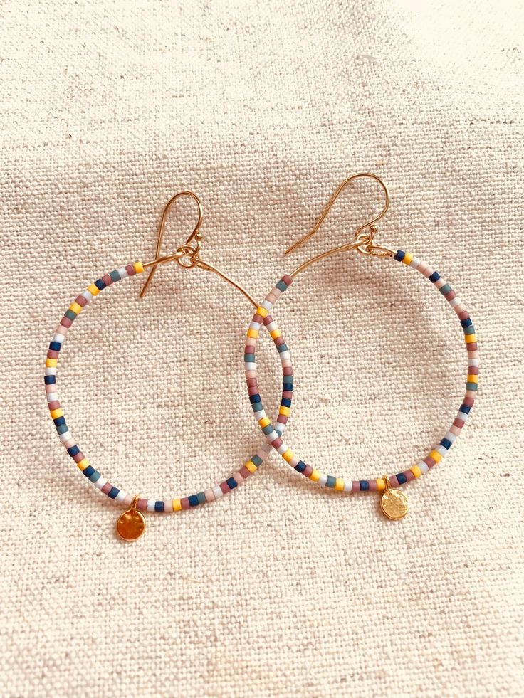 This listing is for one pair of beaded hoop earrings.  The beads are Miyuki Delicas Japanese glass beads.  Bead colors: Blue, Turquoise, baby blue, light pink, mauve, ochre  The ear wire and hoop wire are gold filled.  The gold blank charm that dangles at the bottom of the hoop is gold vermeil.  These earrings are light on the earlobe and add a pretty pop of color and movement!  Measurement: from the top of the ear wire to the bottom of the vermeil round charm is 2 1/4 inch.  What is Gold Filled Adjustable Circular Beaded Earrings With Tiny Beads, Colorful Round Beads Earrings For Everyday, Colorful Round Bead Earrings For Everyday, Adjustable Hoop Earrings With Tiny Beads, Nickel-free Hoop Earrings With Heishi Beads, Hoop Beaded Earrings With Spacer Beads, Colorful Beaded Earrings For Everyday, Everyday Hoop Beaded Earrings With Ear Wire, Hoop Earrings With Tiny Beads