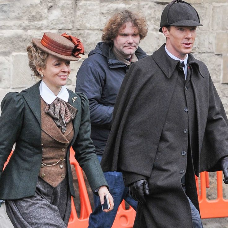 three people dressed in period clothing walking on a tarp