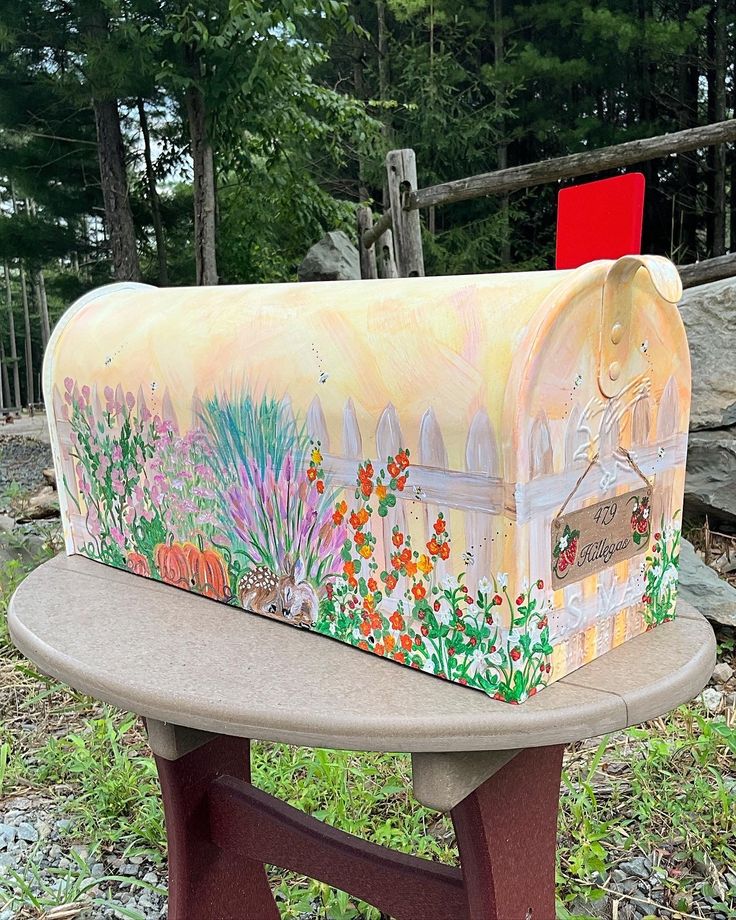 a painted mailbox sitting on top of a wooden bench