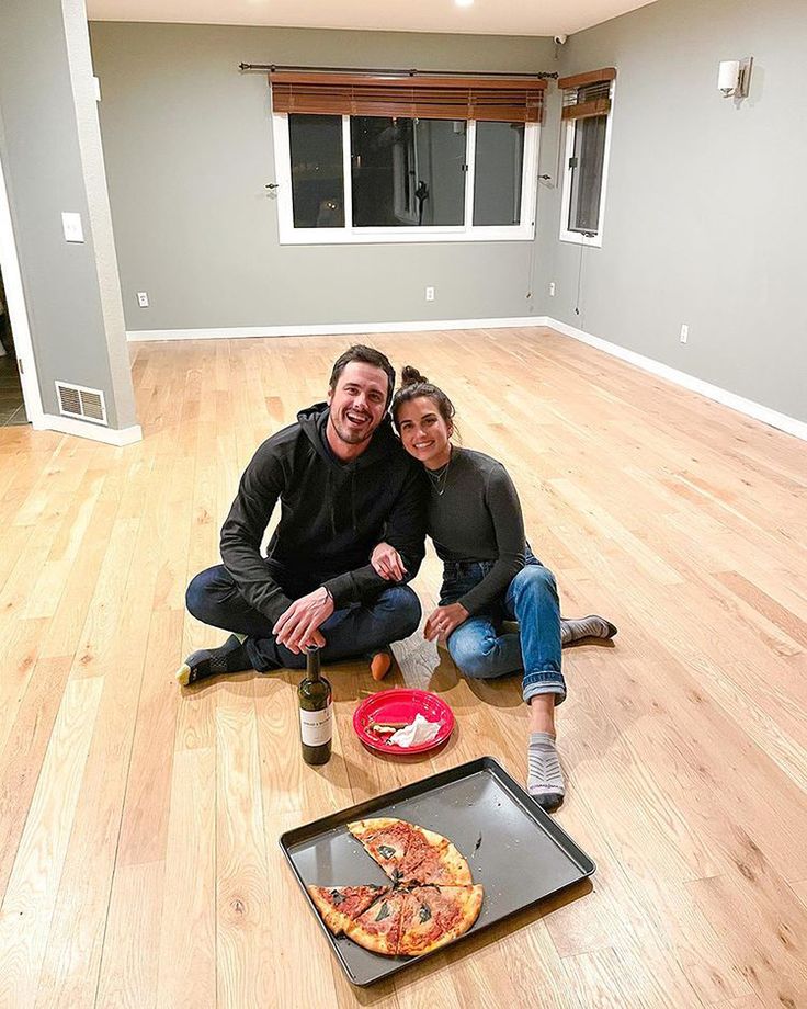 two people are sitting on the floor with pizza and soda in front of them,