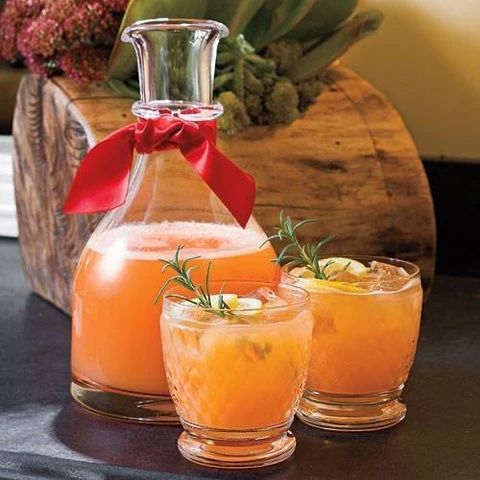 three glasses filled with orange juice and garnished with a red bow sit on a table