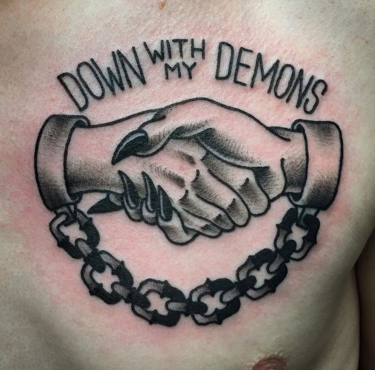 a chest tattoo with two hands holding each other and the words down with demonss on it