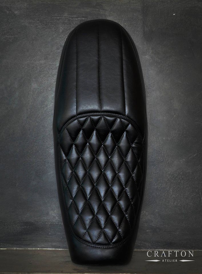 the back end of a black motorcycle seat with diamond quilting on it's sides