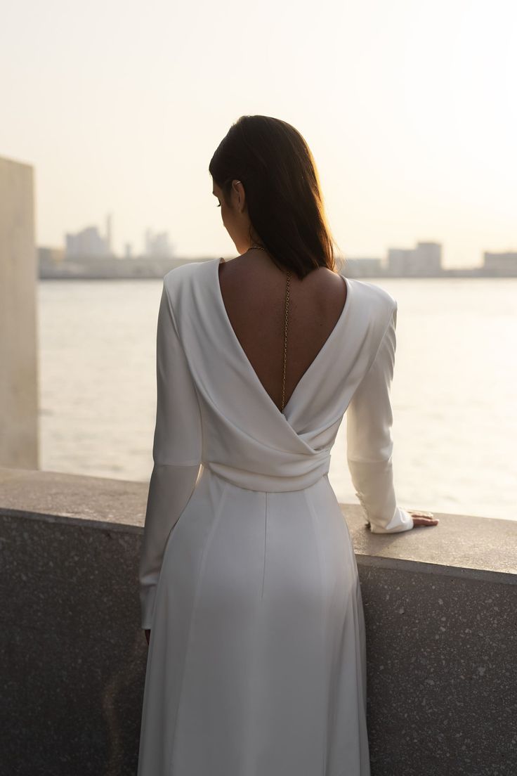 the back of a woman's dress as she looks out over water at sunset