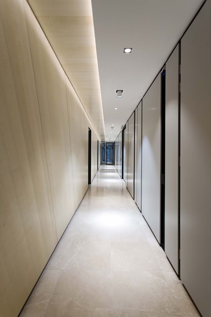 an empty hallway with glass doors leading to another room on either side and the floor is white