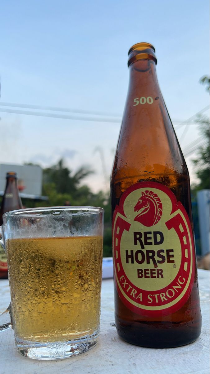 a beer bottle and glass sitting on a table with a blue sky in the background