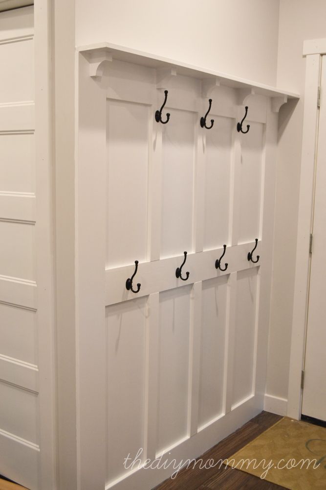 an image of a white room with hooks on the door and some drawers in it