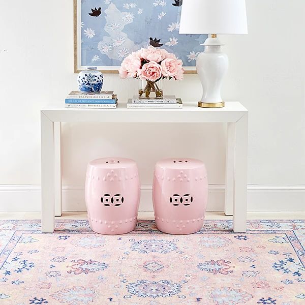 two pink stools sitting on top of a rug in front of a white table