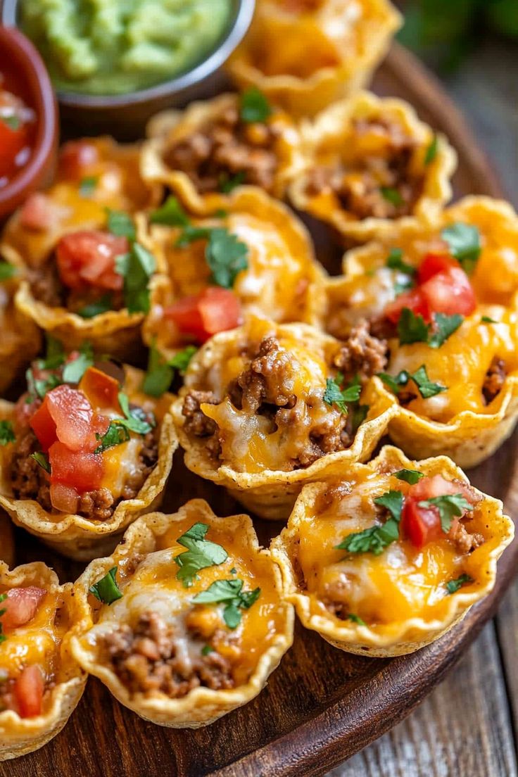 mini taco cups on a wooden platter with guacamole and salsa