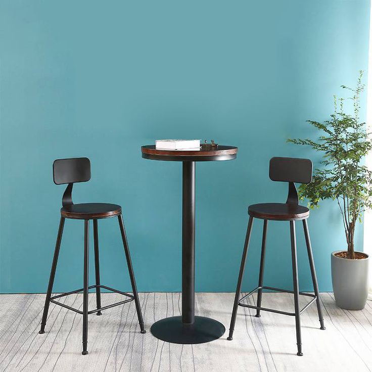 two chairs and a table in front of a blue wall with a potted plant