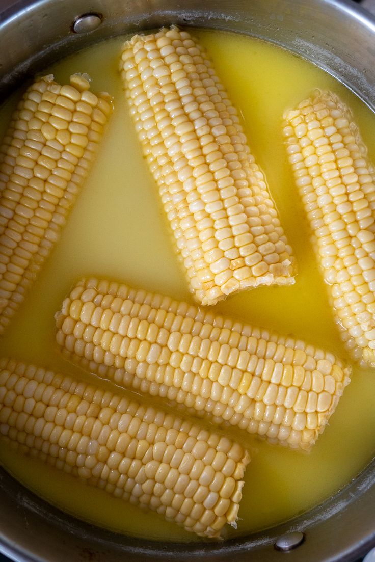 corn is being cooked in a pot on the stove with yellow liquid and water inside