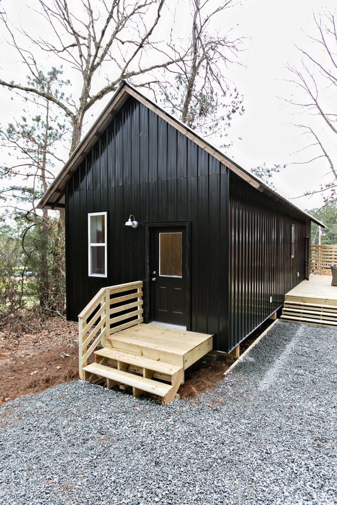 a small black cabin with steps leading up to it