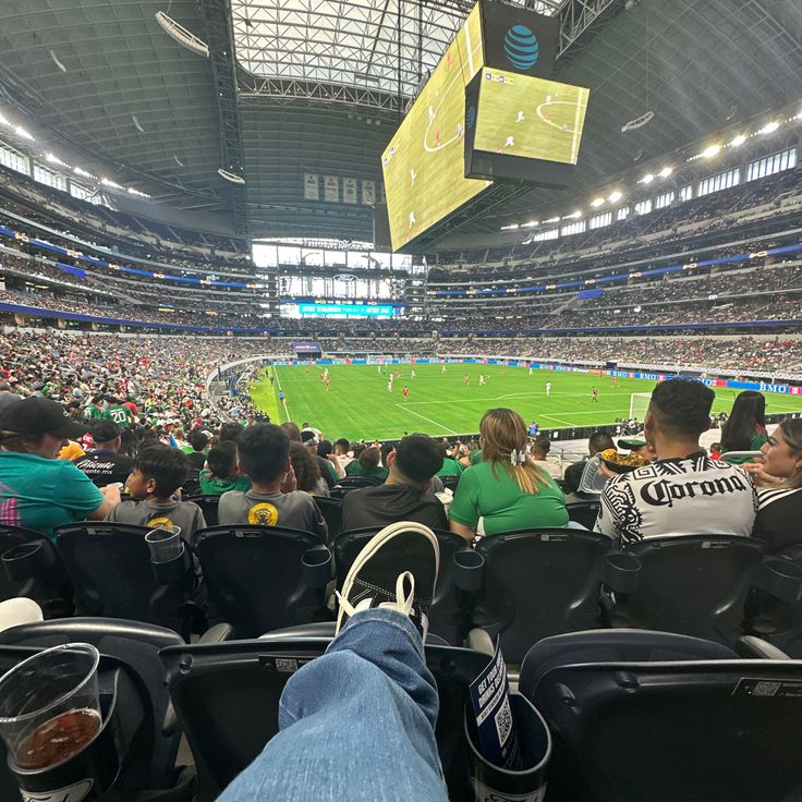 people are sitting in the stands at an indoor soccer game, with one person's feet up