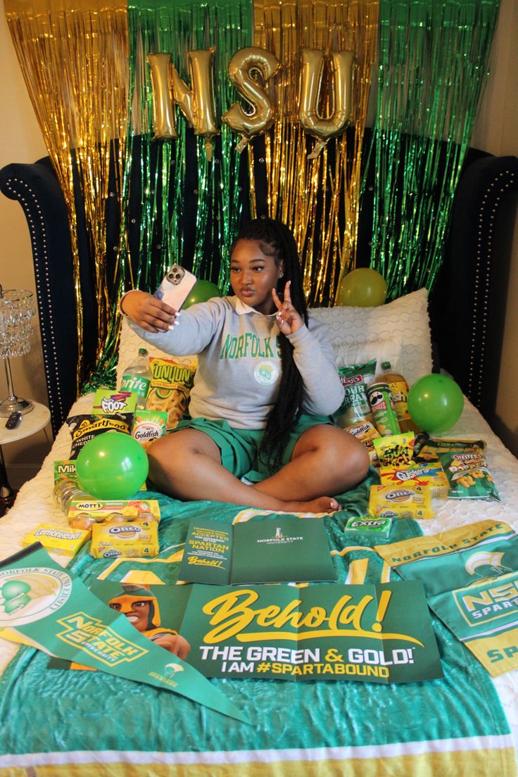 a woman sitting on top of a bed surrounded by green and gold decorations, holding up her peace sign