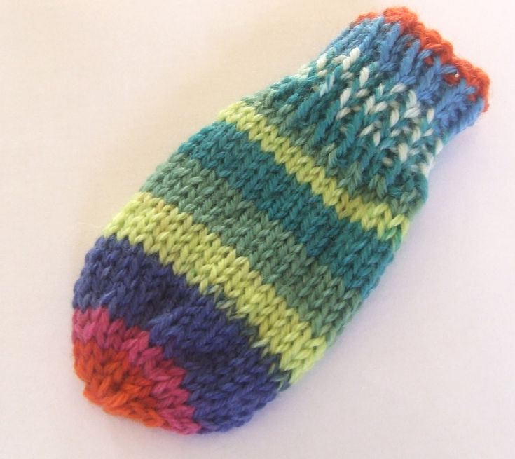 a multicolored knitted mitt sitting on top of a white table