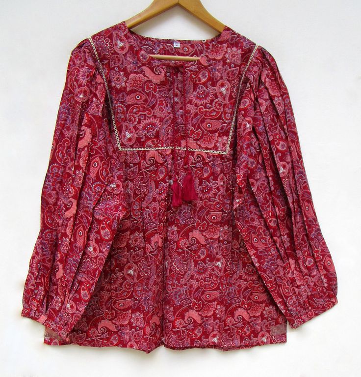 "ITEM DESCRIPTION reddish chili color ethnic print blouse and tops - Henley neckline with tassel blouse - long sleeve with button bohemian blouse - with lace Features: Long sleeve, Henley neck, blouse Material: Cotton Voile Fabric: 100% cotton soft light weight ethnic print fabrics Sleeve Length = 22 inch For more sizes & their measurement, please refer our below chart to understand the sizes variations available with us For your size requirement, please mention your size in seller note at the t Ethnic Tops, Bandhani Lehenga, Long Sleeve With Buttons, Cotton Short Tops, Cotton Tops Designs, Bohemian Blouse, Tassel Blouse, Paisley Print Blouse, Tunic Designs