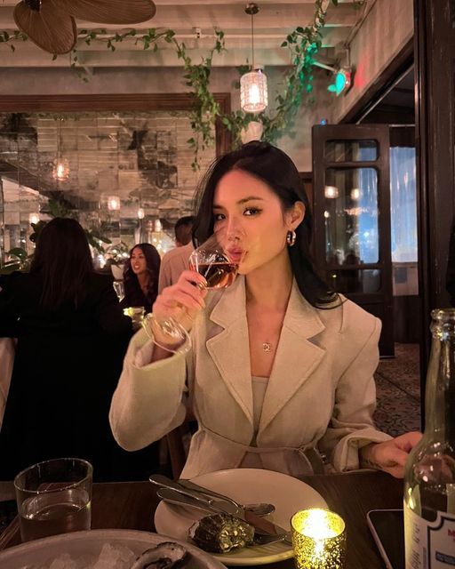 a woman sitting at a table drinking wine