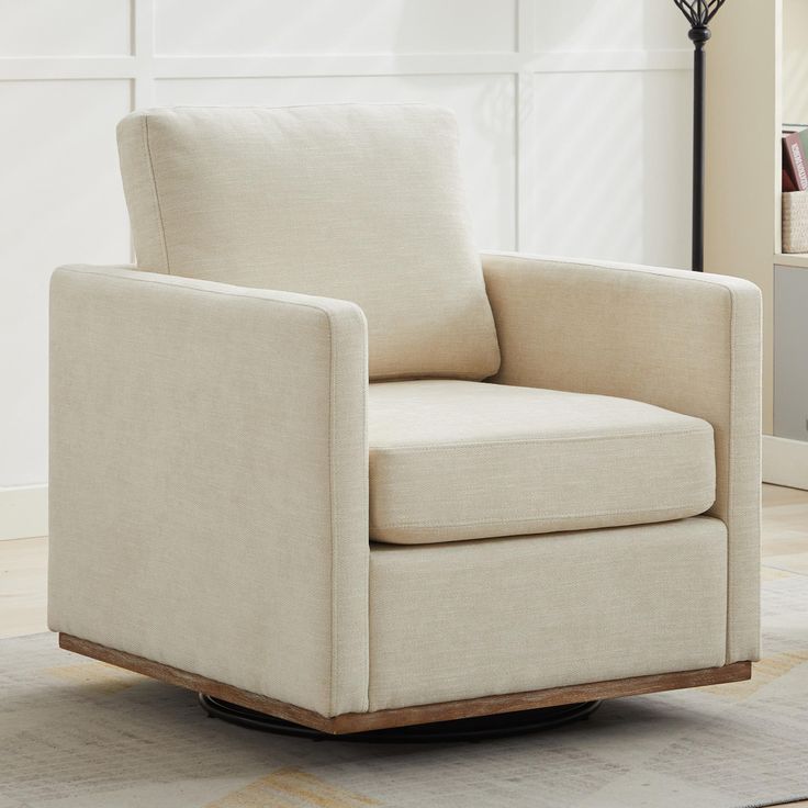 a white chair sitting on top of a wooden floor next to a lamp in a living room