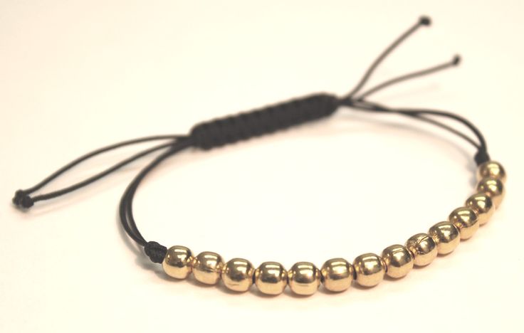 a gold beaded bracelet on a black cord