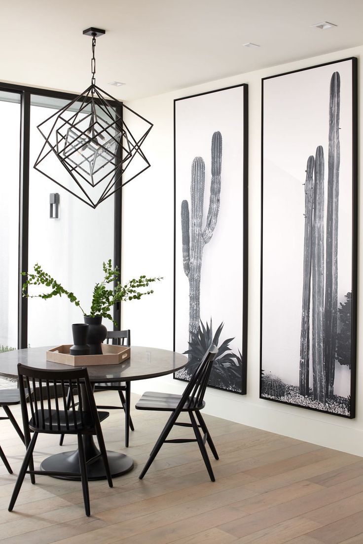 a dining room table with four chairs in front of two large cactus pictures on the wall