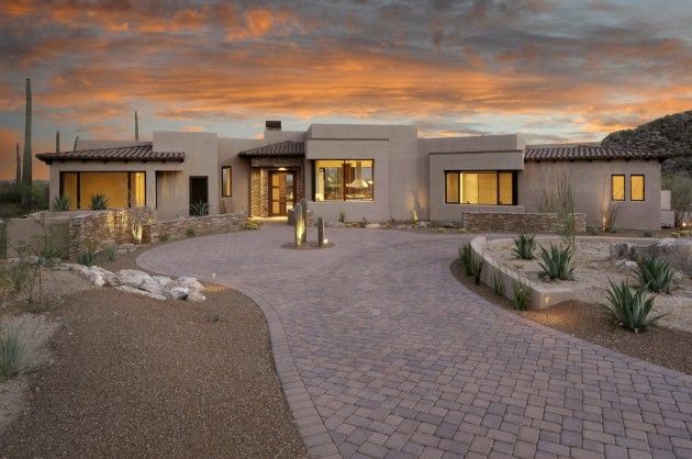 a large home with a driveway leading to the front door and entry way at sunset