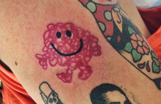 a close up of a person's arm with tattoos on it and a smiley face