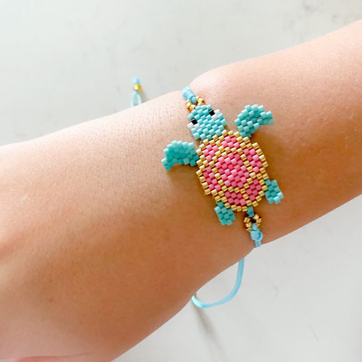 a woman's arm with a beaded turtle bracelet on it