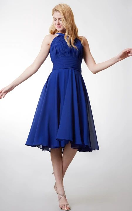 a woman in a blue dress is posing for the camera with her arms spread out