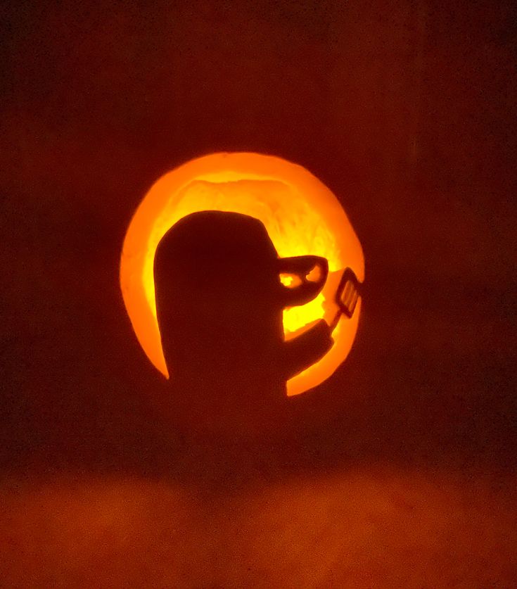 a carved pumpkin with the shape of a man's head in front of it