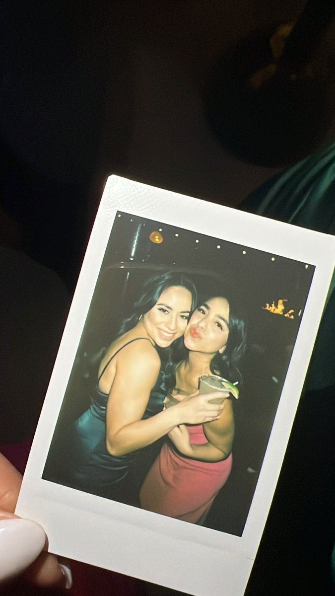 two women are holding up a polaroid photo