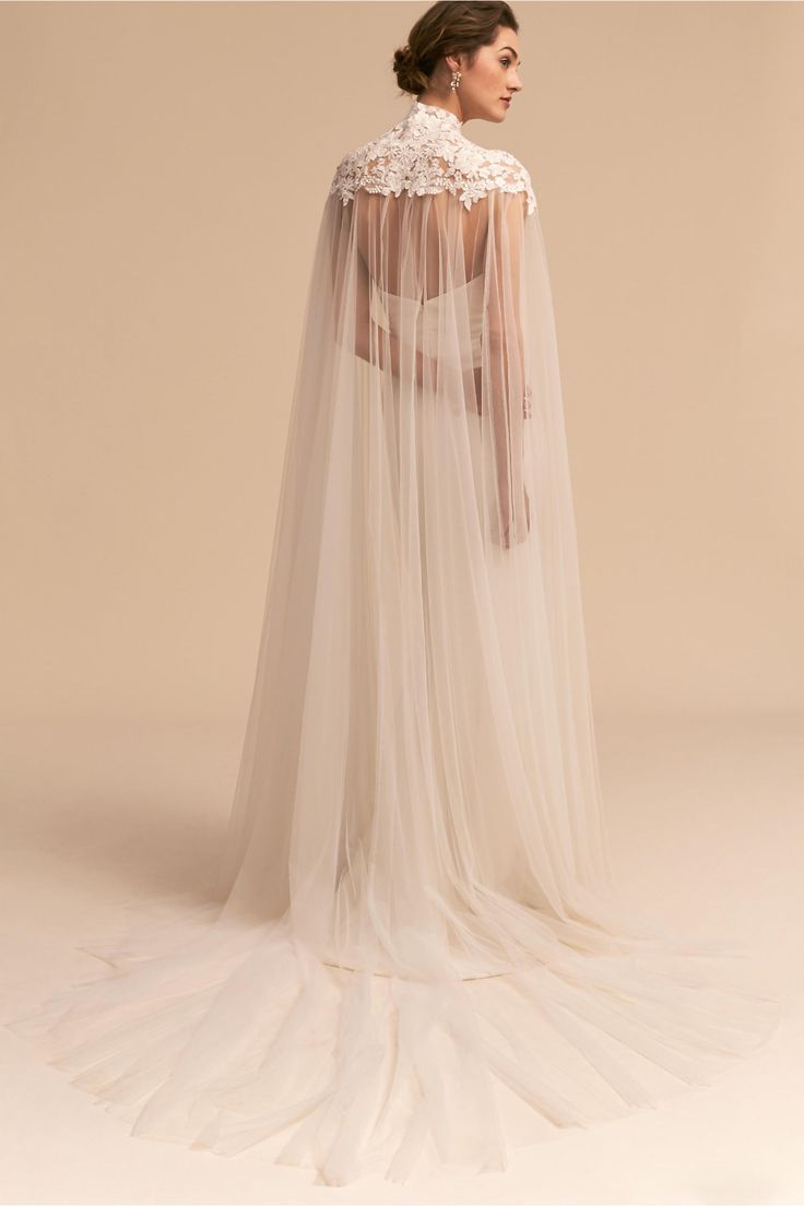 a woman in a wedding dress with a long veil on her head and shoulders, standing back to back