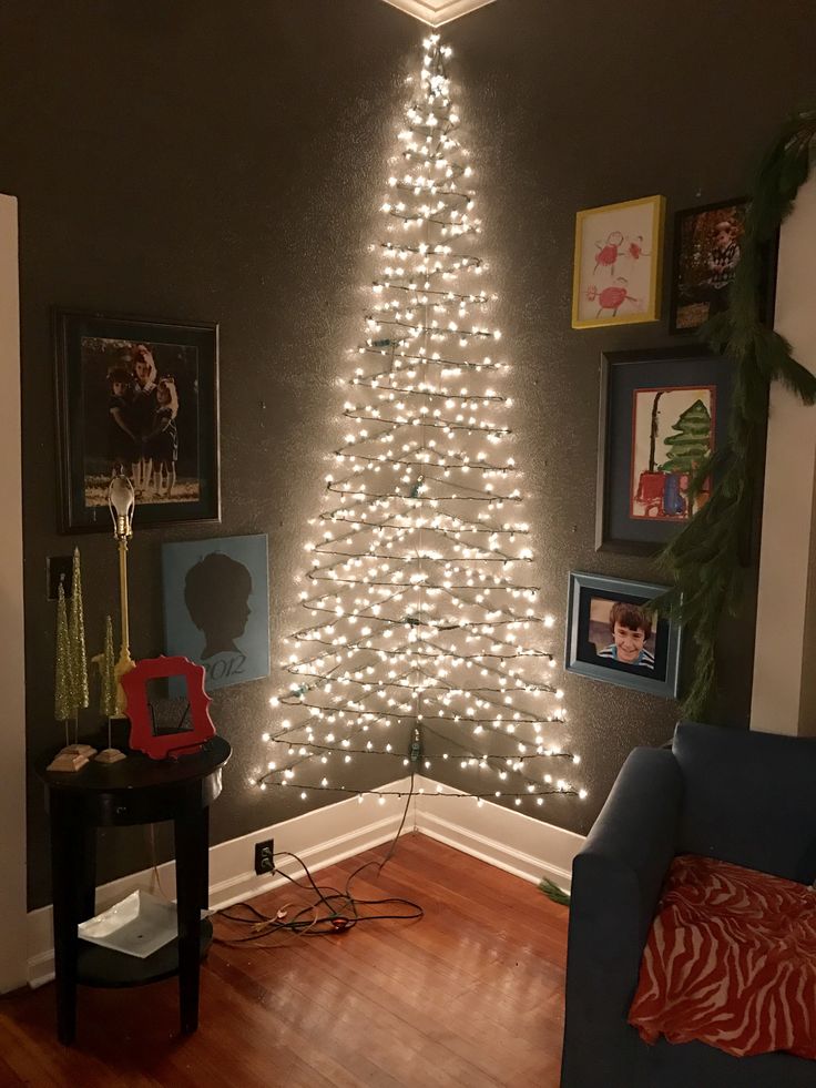 a living room with a christmas tree in the corner and lights on the wall above it