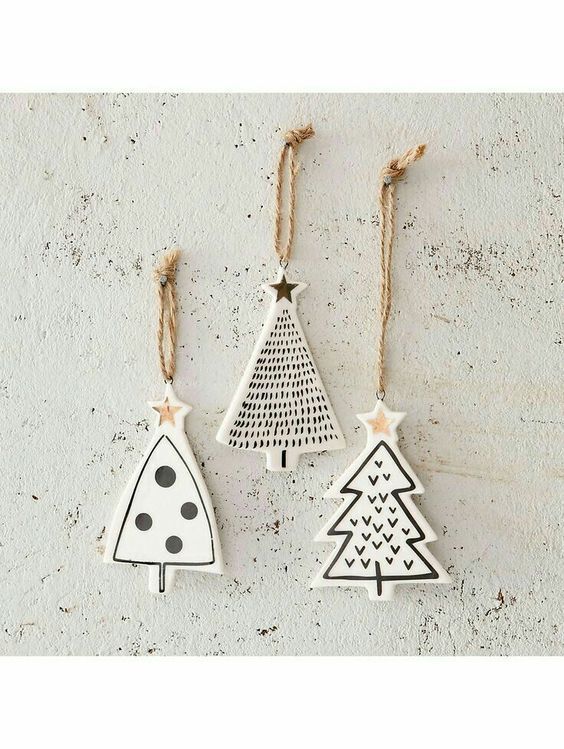 three wooden christmas trees hanging from twine on a white wall, one with black dots