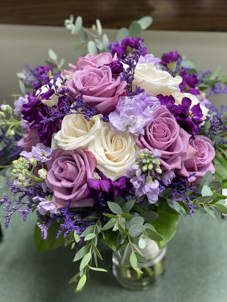 a vase filled with purple and white flowers sitting on top of a green tablecloth