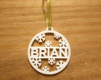 a wooden ornament with the word britain in snowflakes hanging from a gold ribbon