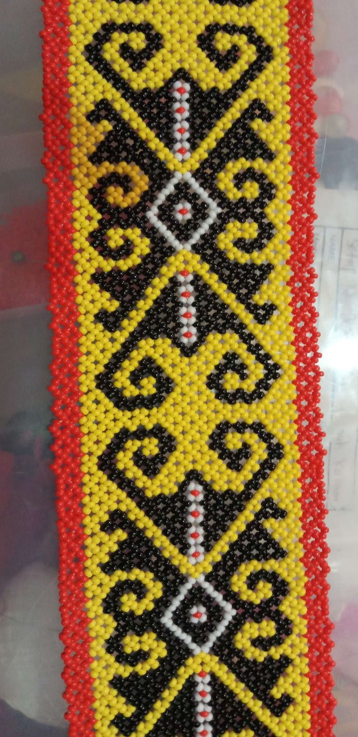 a beaded bracelet with black, yellow and red designs on the outside of it