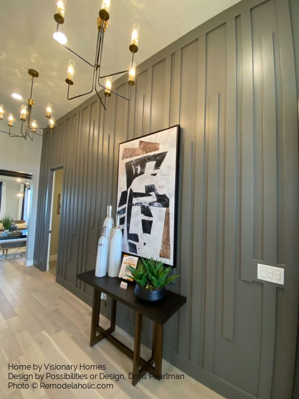 a painting hangs on the wall next to a table with a plant and vases