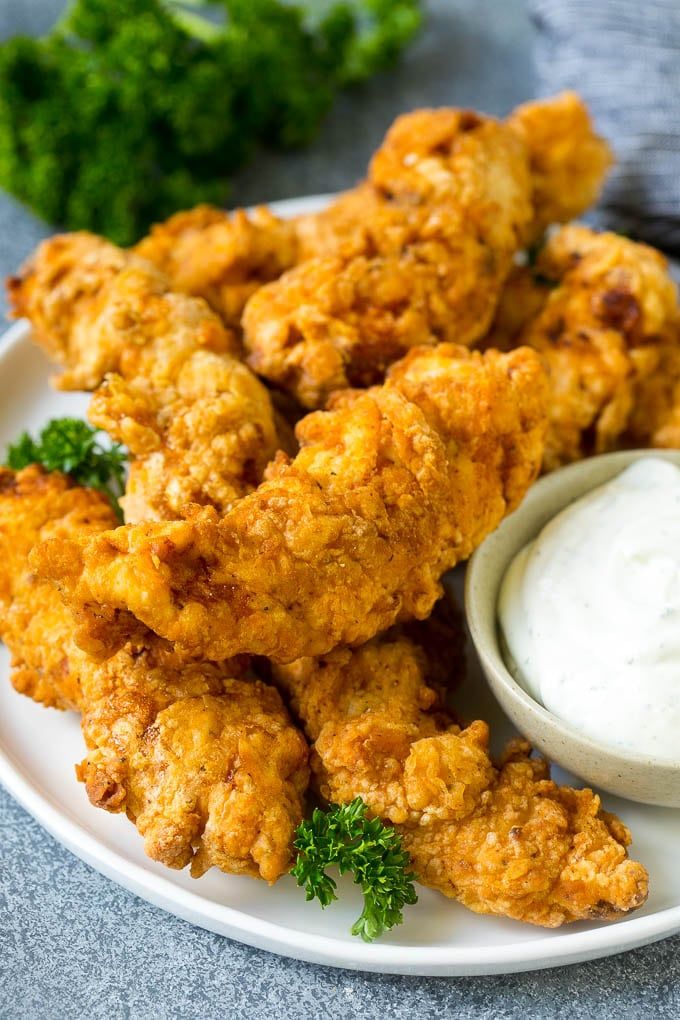 fried chicken on a plate with ranch dressing and garnished parmesan dip