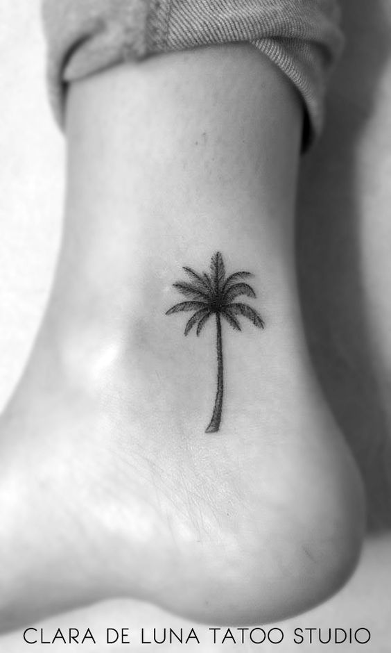 a small palm tree on the ankle tattoo is shown in black and white, as well as