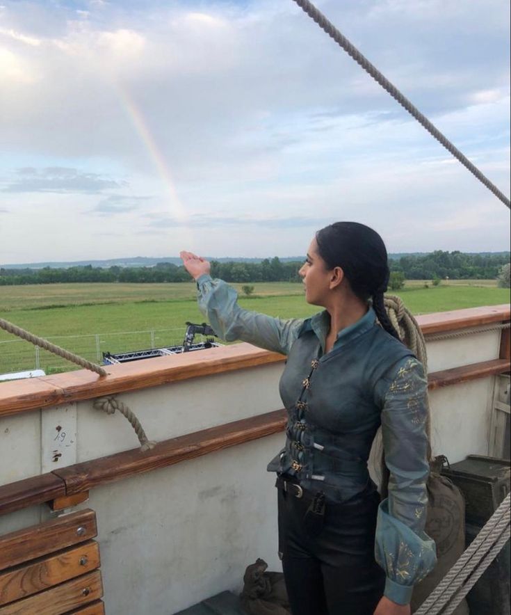 a woman standing on top of a boat next to a rainbow