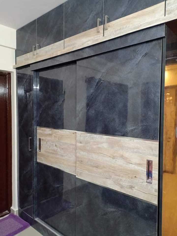 a bathroom with black marble walls and wooden trim around the shower door, along with a purple rug on the floor