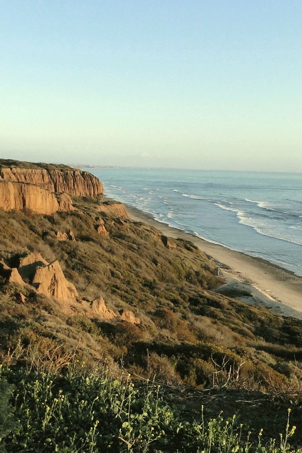 the beach is next to some cliffs by the water's edge and there are no people on it