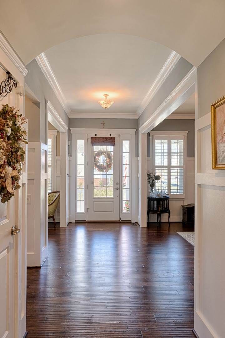 an empty entry way with wood floors and white trim on the door, framed by two wreaths