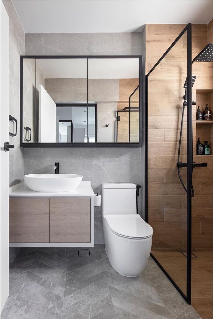 a bathroom with a toilet, sink and mirror in it's center wall next to a walk in shower