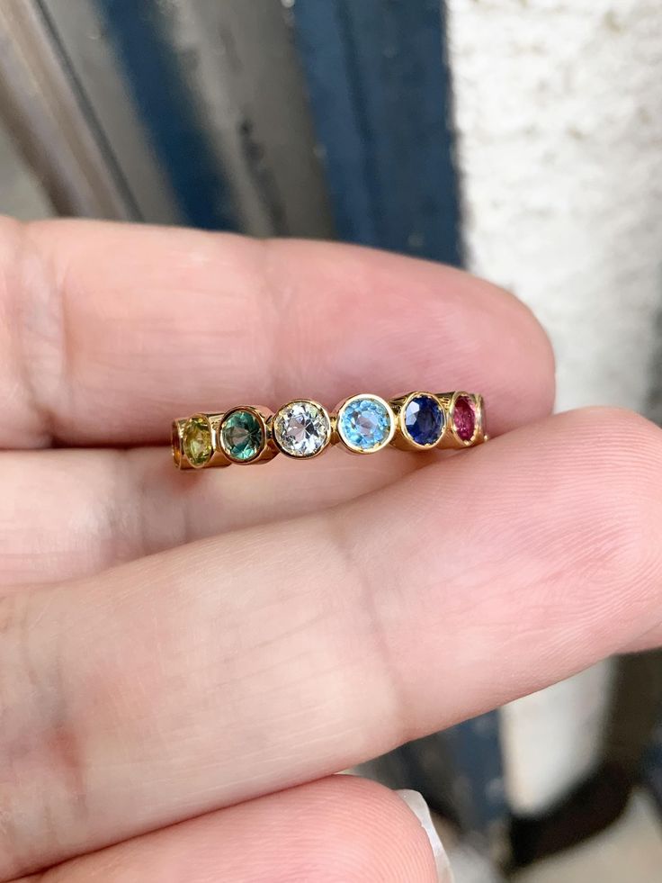 a person is holding three different colored stones in their left hand and the other one has a yellow gold band