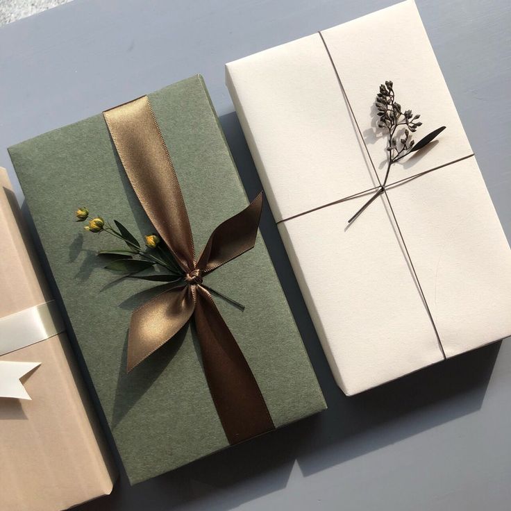 three wrapped gift boxes with ribbons and flowers on them