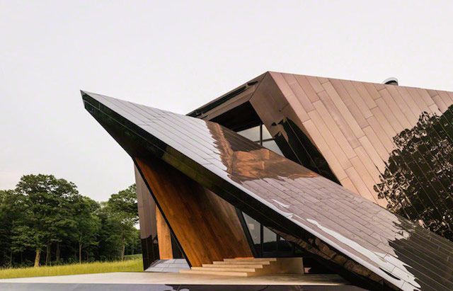 a large triangular shaped building sitting on top of a lush green field next to trees