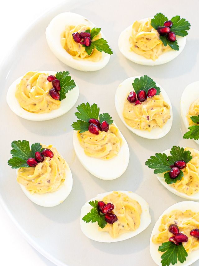 deviled eggs decorated with garnish and parsley on a white plate